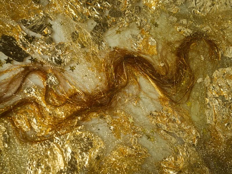 Abstract gold leaf and resin with wavy brown texture.