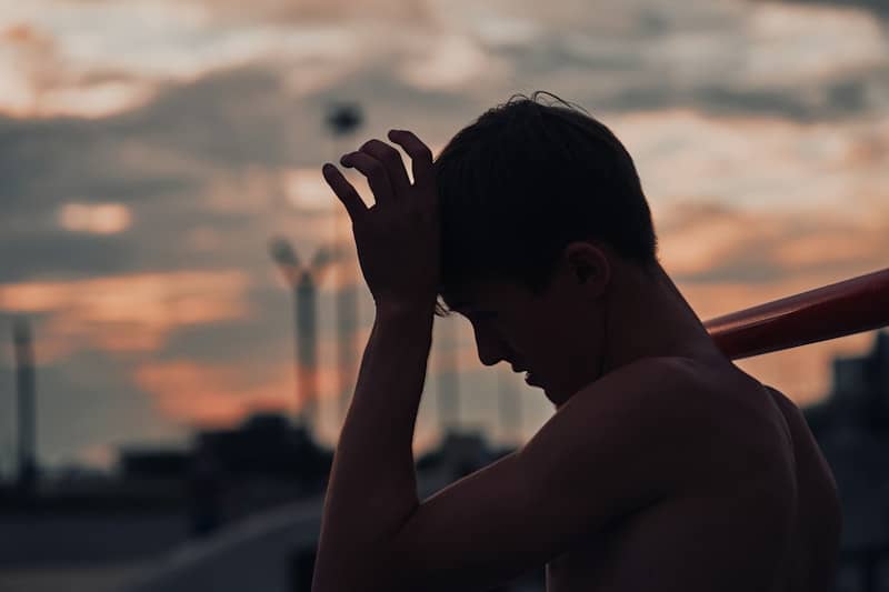 Silhouette of a tired baseball player with bat at sunset