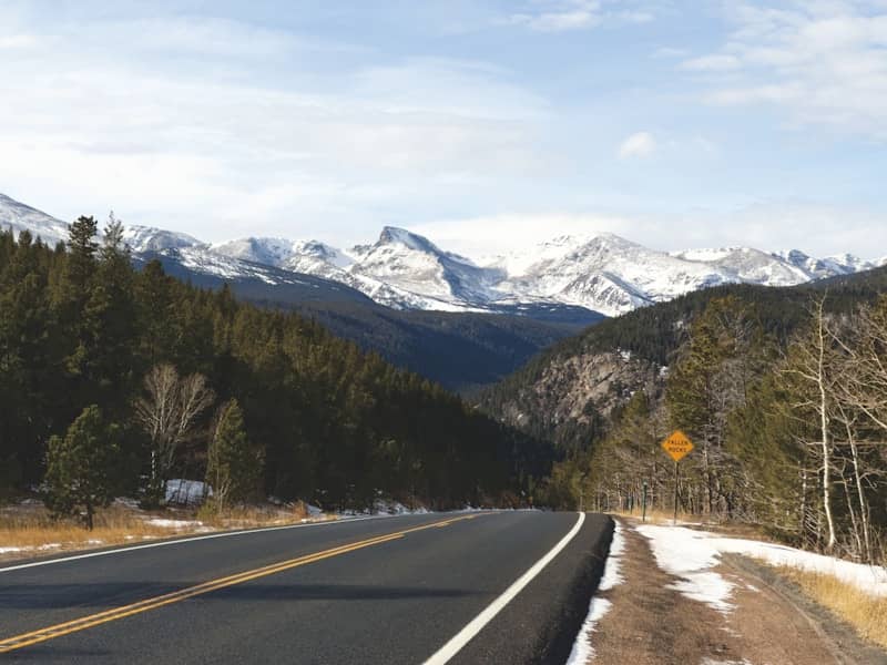 A scenic road leads to snow-capped mountains.