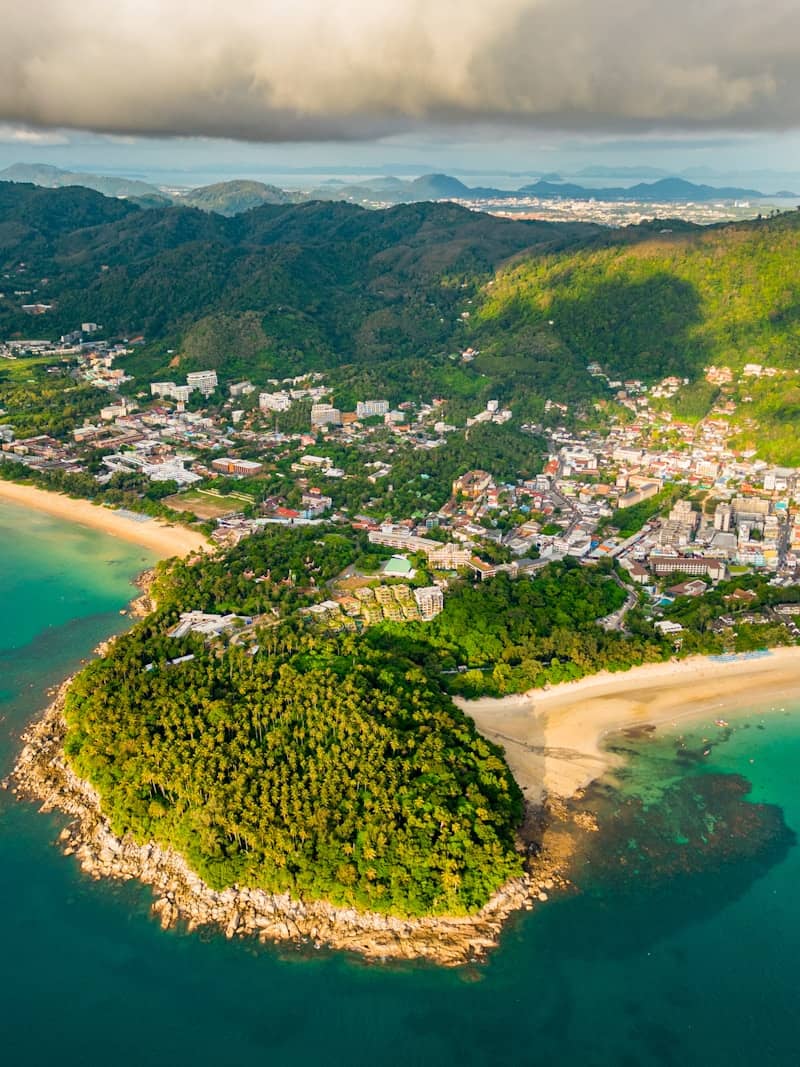 Aerial view of a tropical coastal town with lush green hills.