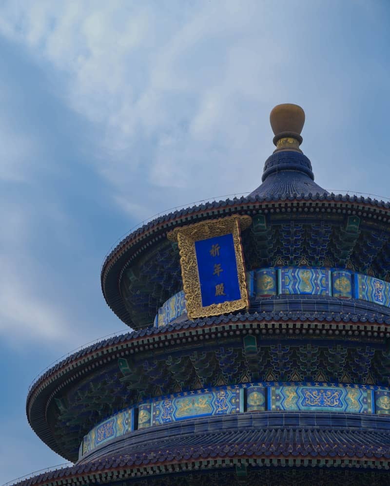 Traditional chinese temple's ornate blue roof and golden finial.