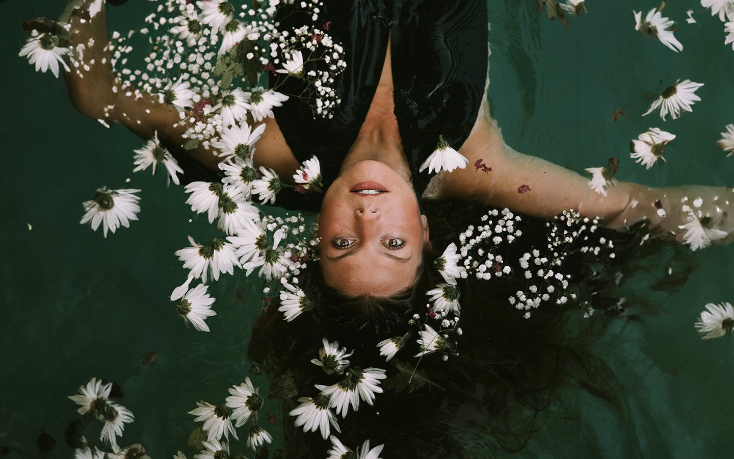 A woman floating in water with flowers