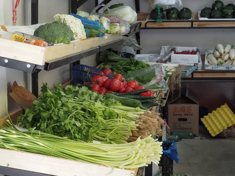 Fresh vegetables displayed on shelves at a market.