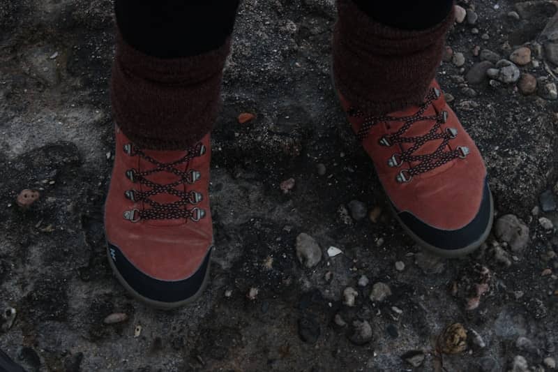 Person wears red boots standing on a rocky surface.