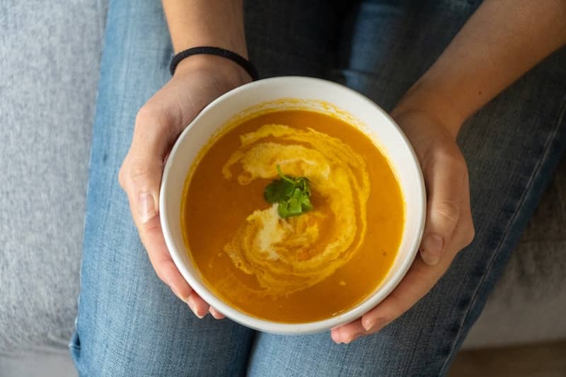 Bowl of butternut squash soup with swirl and herb garnish