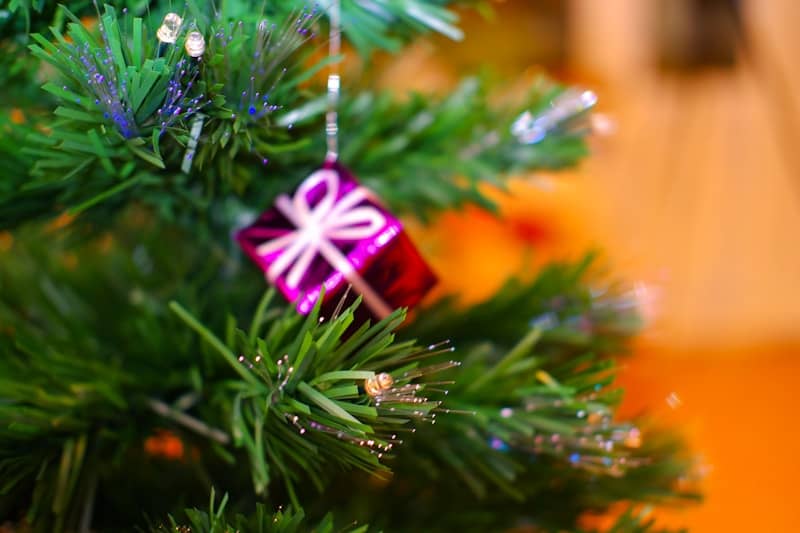 A small pink gift ornament on a christmas tree