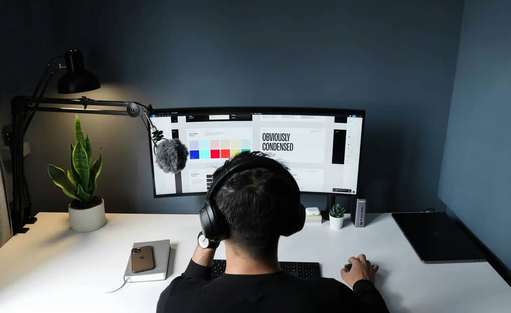 Person working remotely at a desk with dual monitors and a task board
