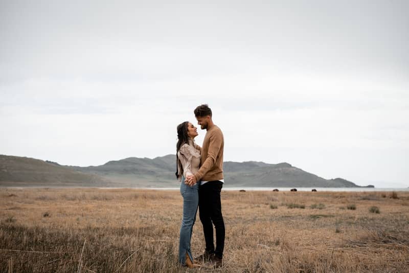 A couple embraces in a field's open space.