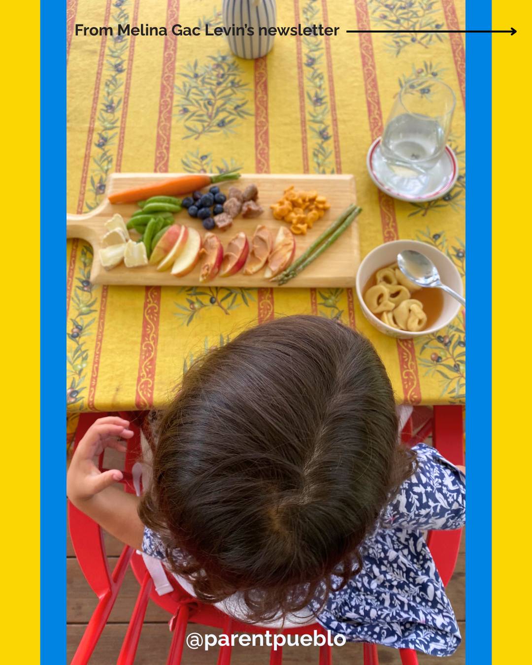 Child with brown hair seen from above and behind, with her lunch set in front of her at a table.