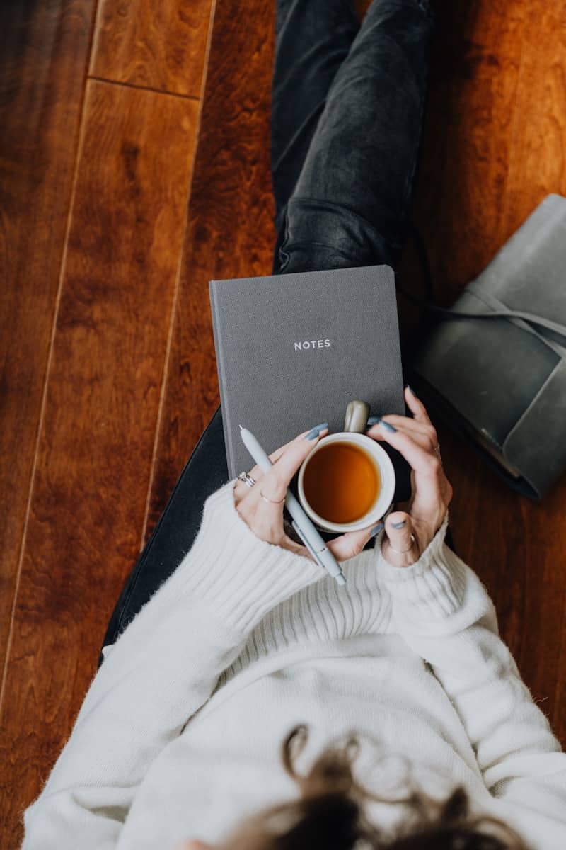 A person sitting on the floor with a laptop and a cup of coffee