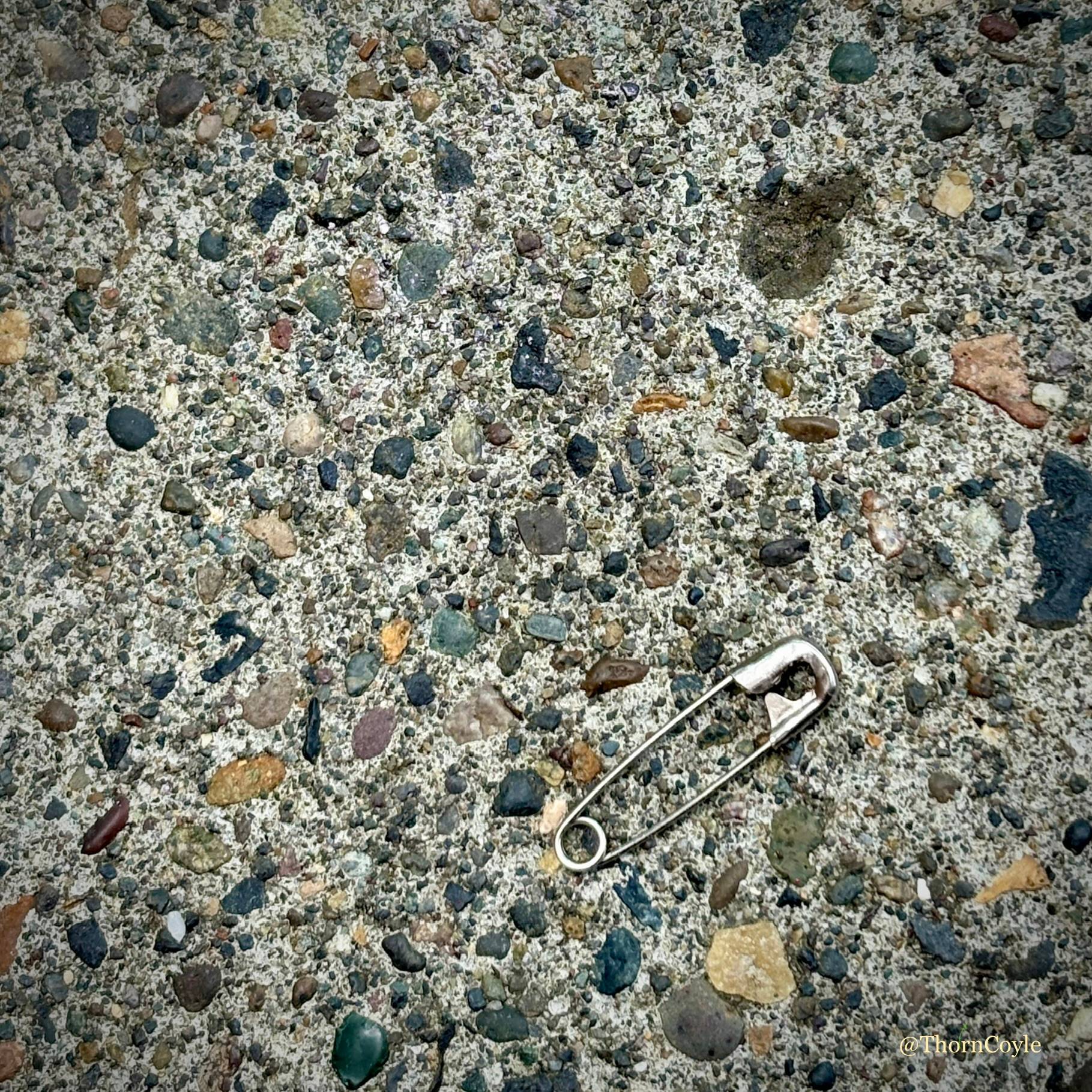 Safety pin on a pebble dash sidewalk
