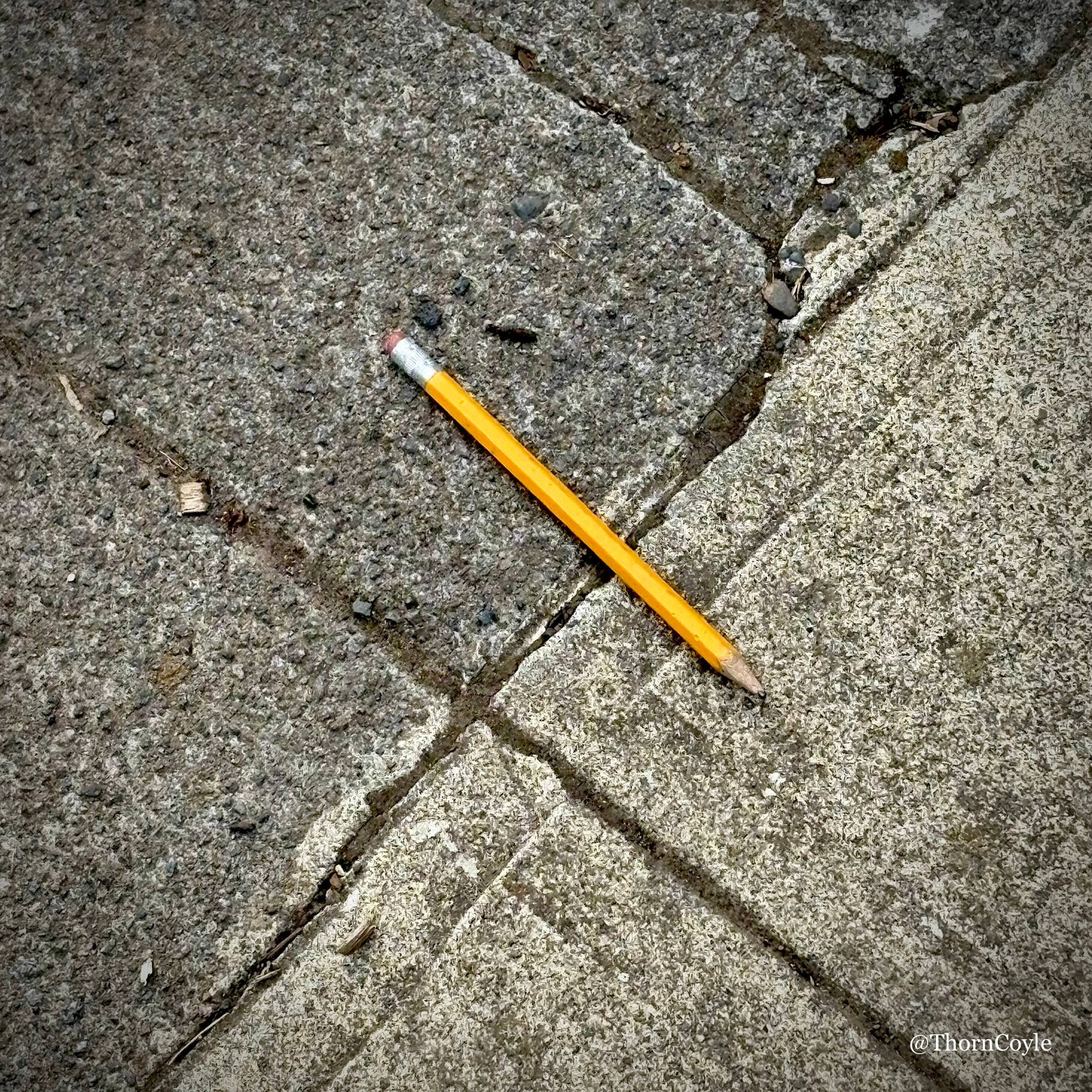 Sharpened yellow pencil on a sidewalk.