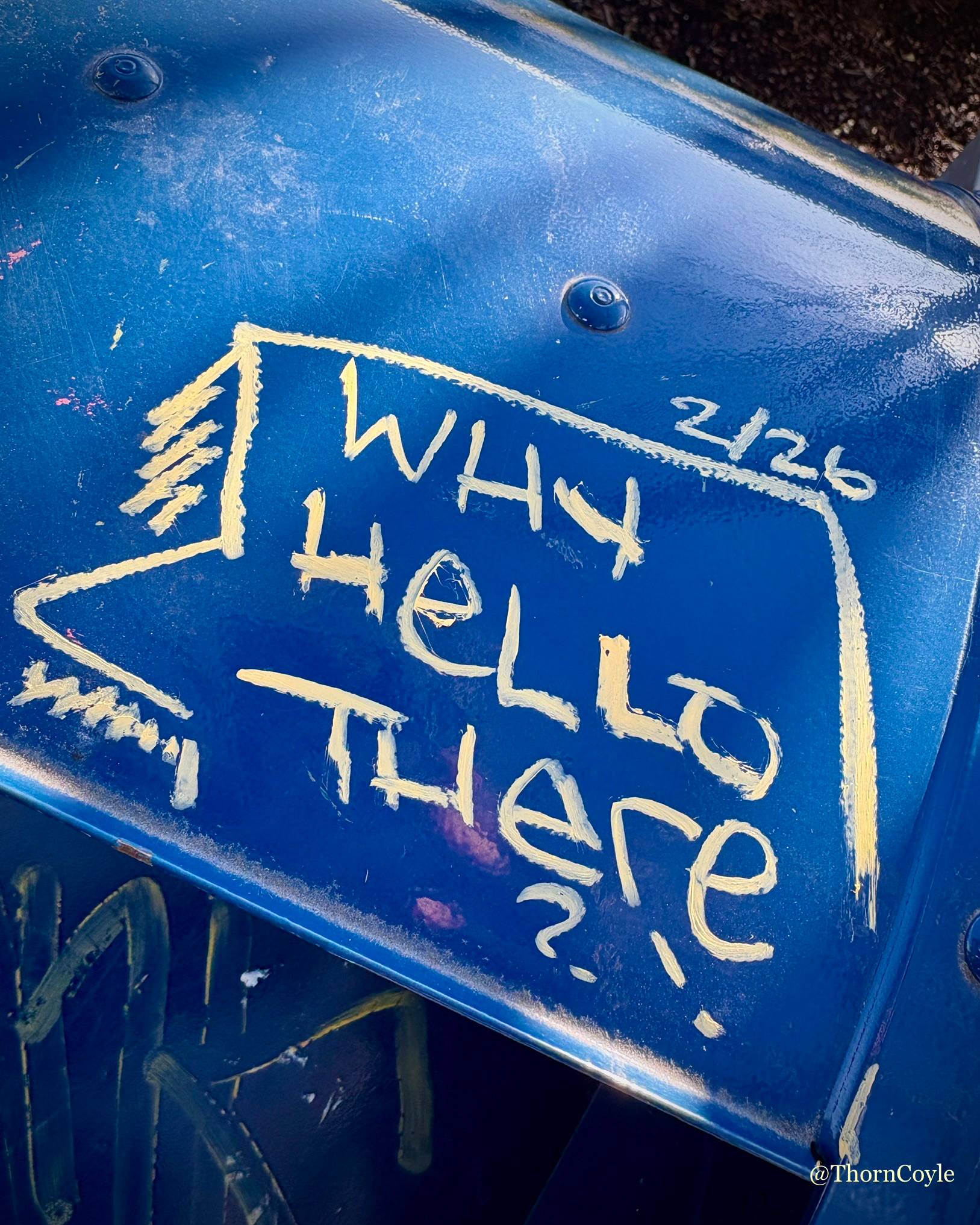 Photo of a sidewalk blue post box with a speech bubble scrawled on it that says “Why hello there?!”