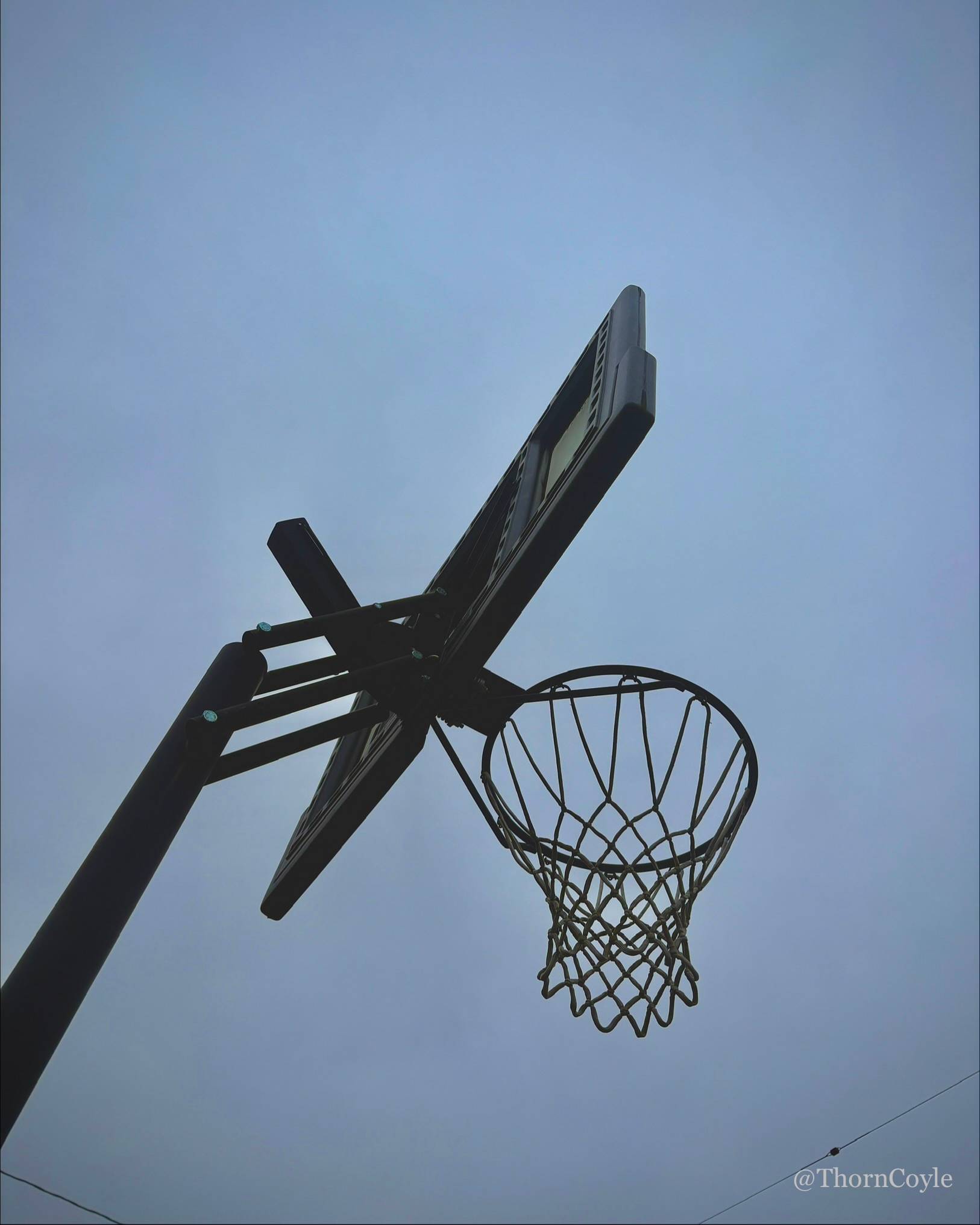 Photo: looking up at a basketball hoop against gray sky