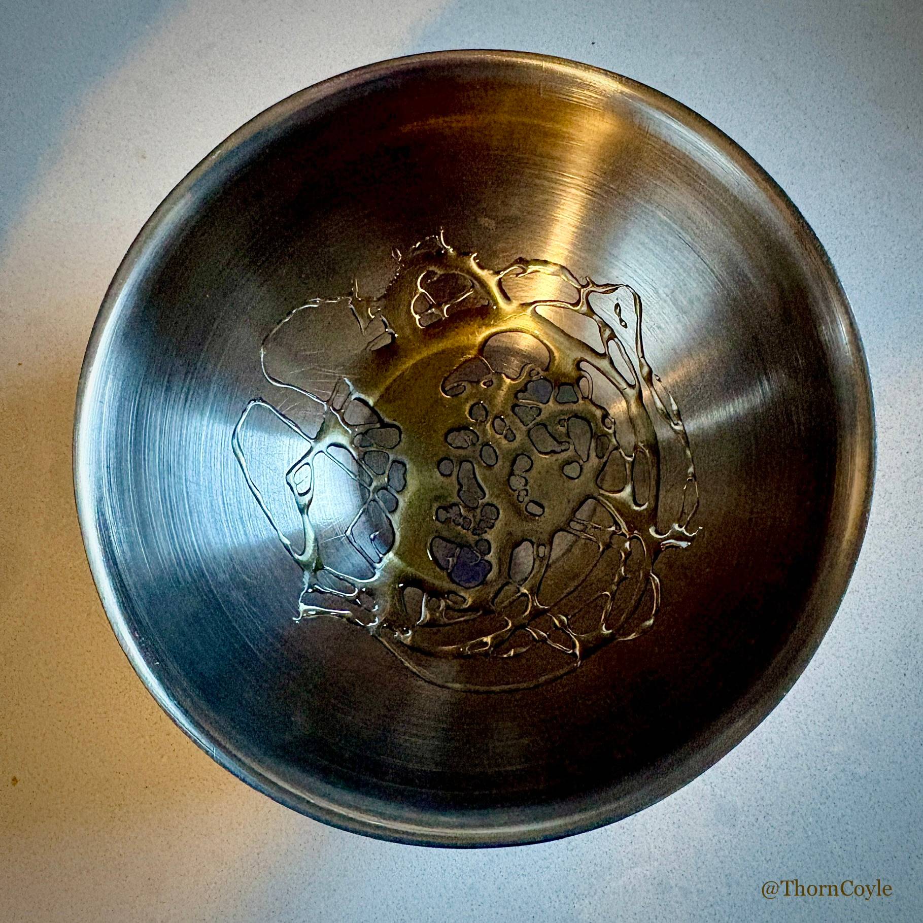 Honey drizzled in the bottom of a metal bowl