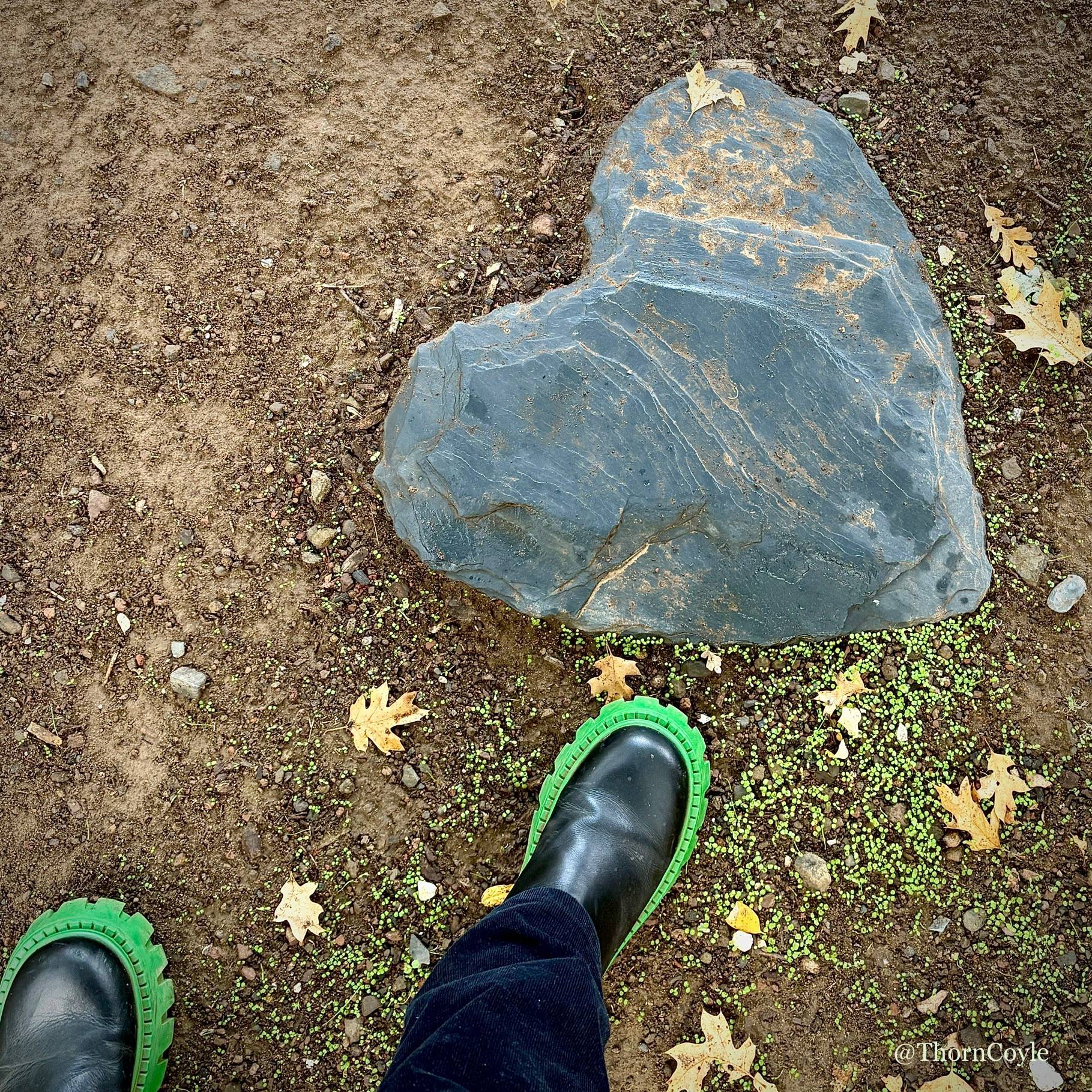 A big slate heart stepping stone and a green soled boot.