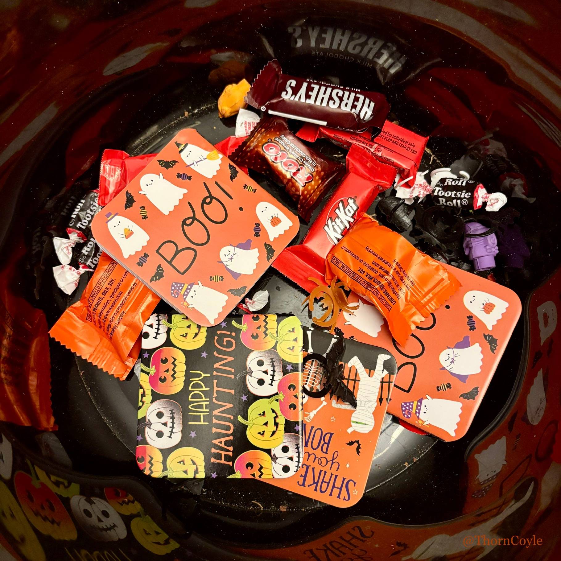 a few candy bars and halloween notebooks in the bottom of a bowl.