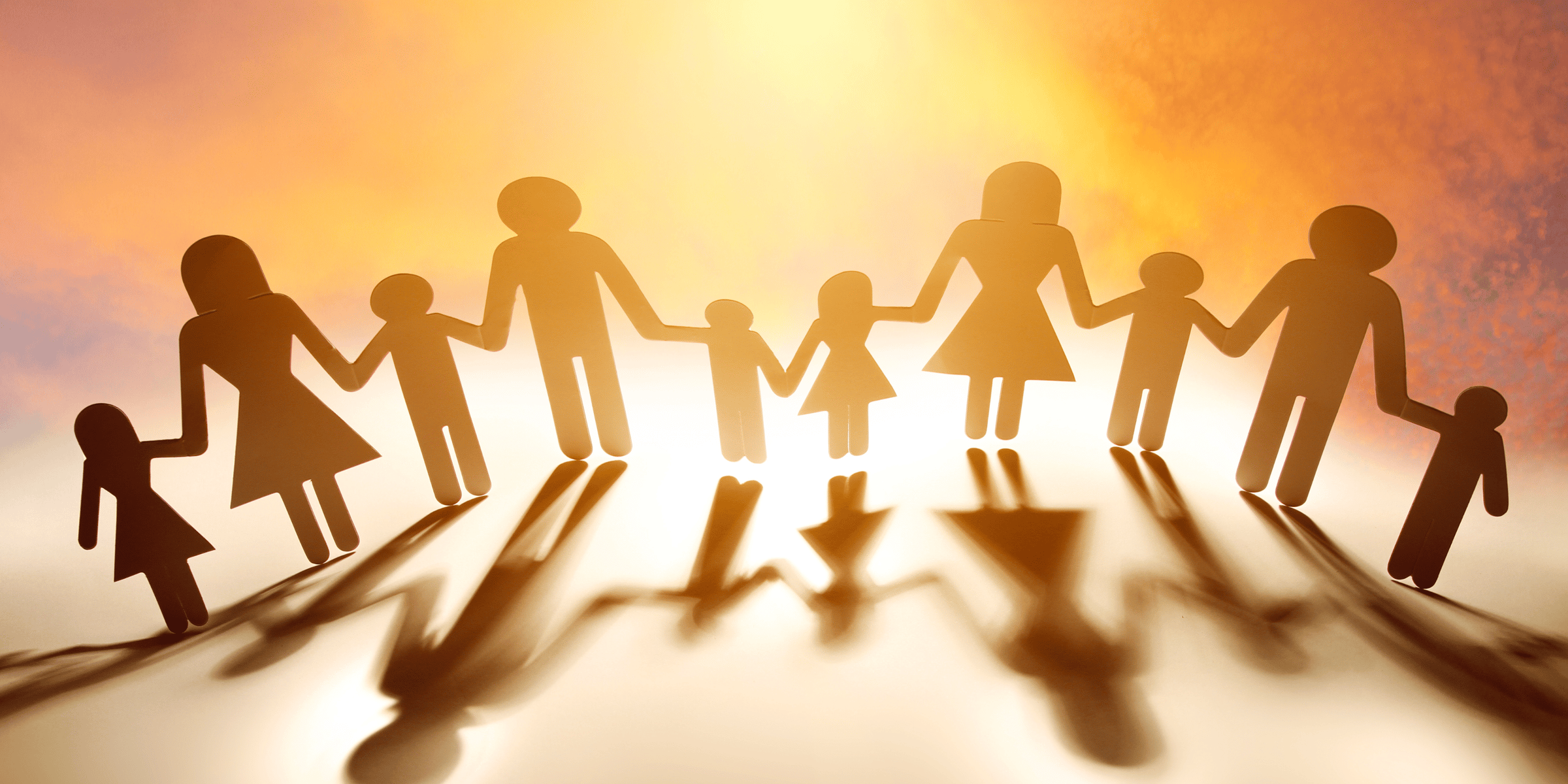 A paper-cutout family holding hands in front of a glowing sunset, symbolizing unity, support, and community in raising resilient children.