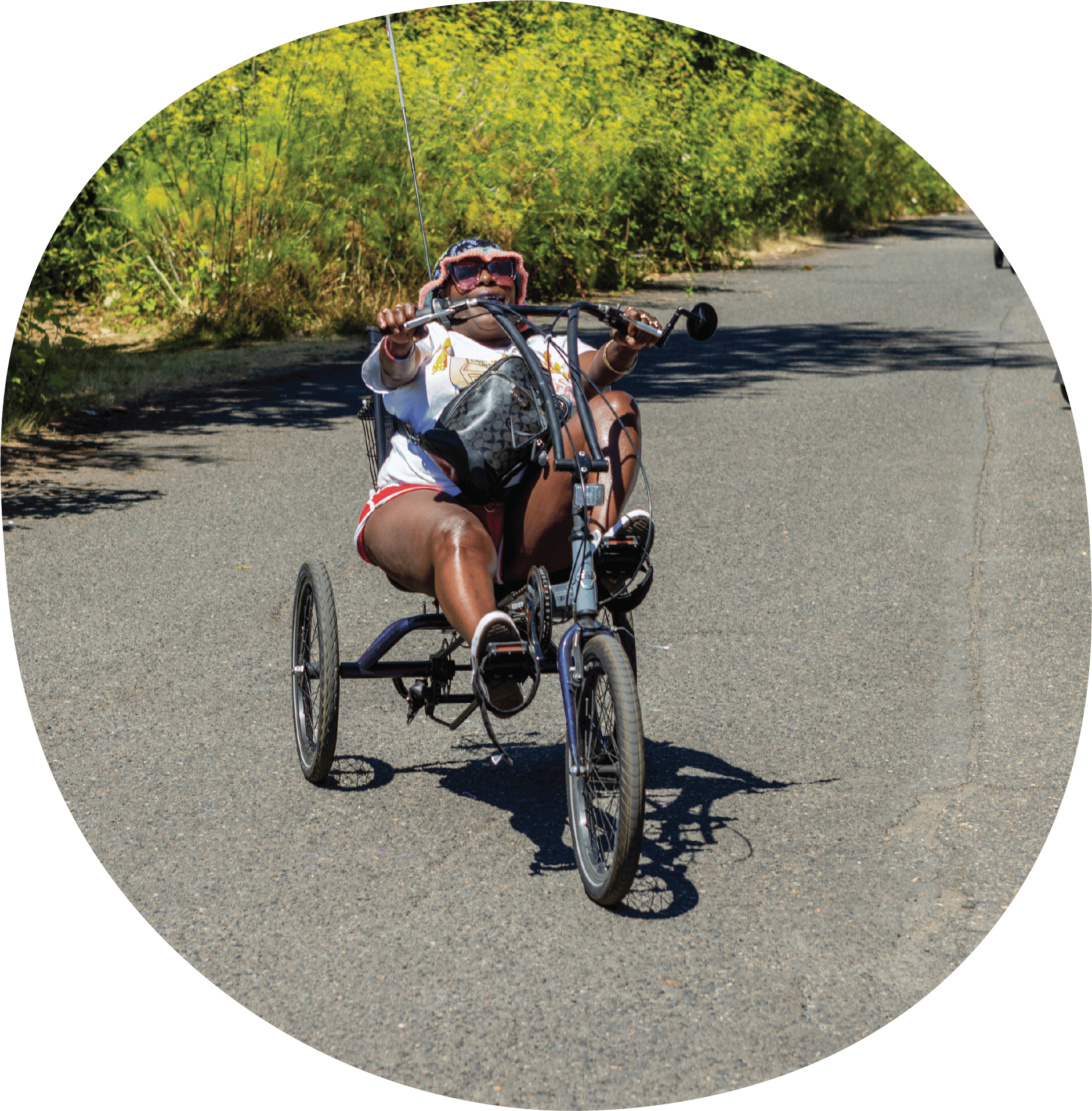 A person smiling is riding on a three-wheel adaptive bike