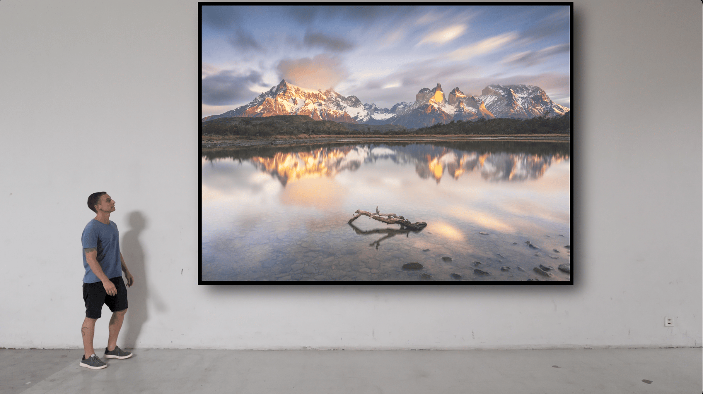 Ale Rodrigues olhando para um quadro com uma fotografia fine art da Patagonia Chilena