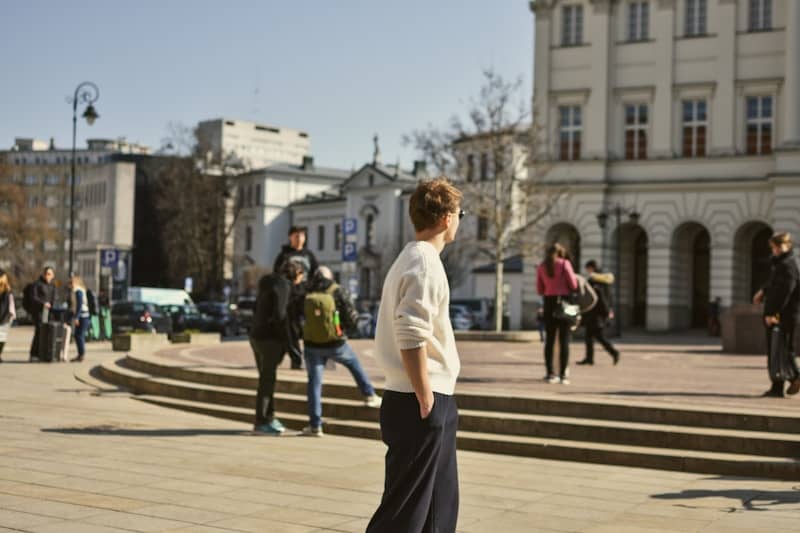 A man stands in a sunny, urban environment.