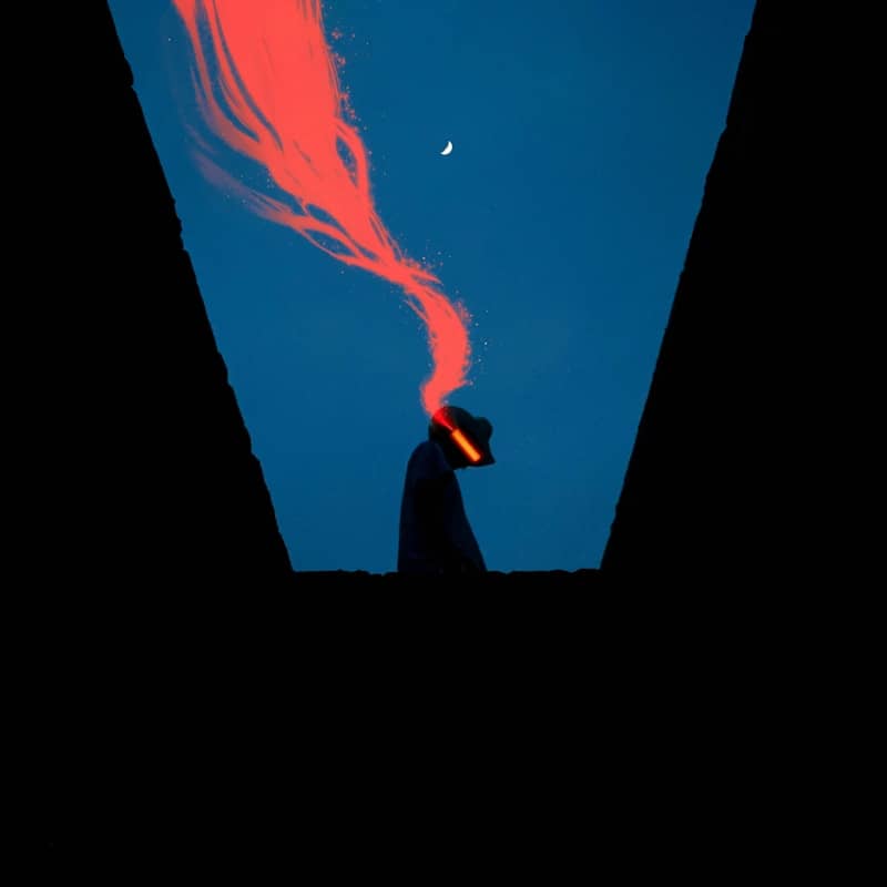 Silhouette with red smoke against a dark blue sky