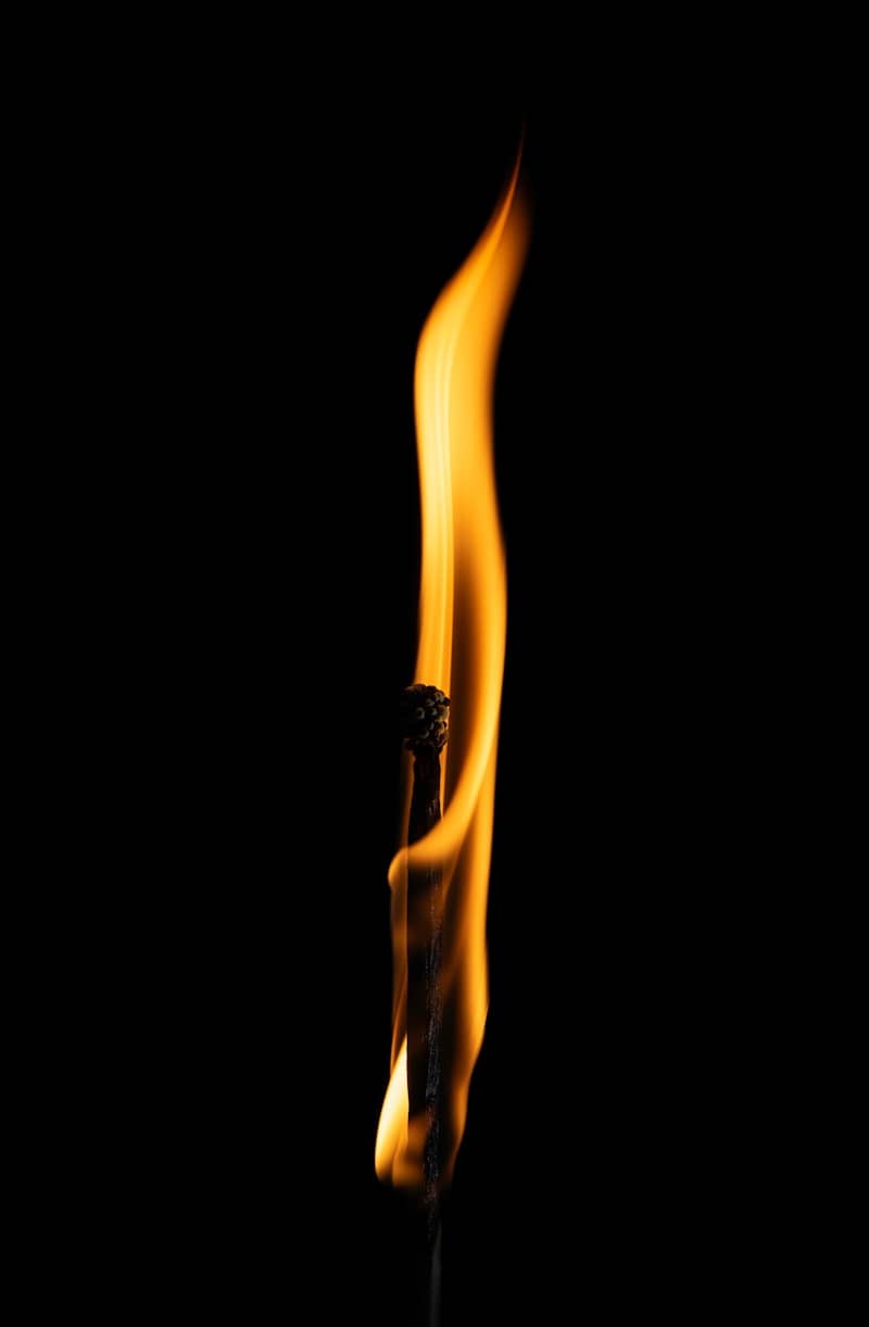 A lit match burning brightly against a black background