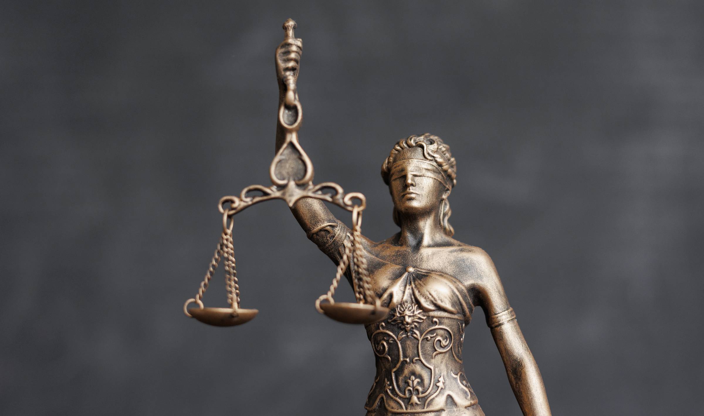 A bronze statue of Lady Justice holding a set of scales