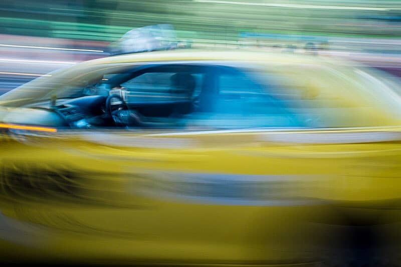 A yellow cab rushes by in a blur