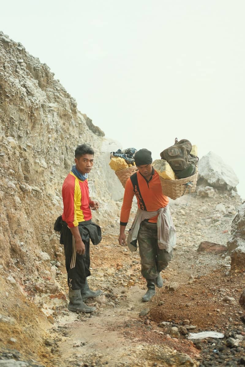 a couple of men walking up a mountain side