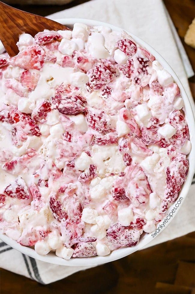 Strawberry shortcake fluff salad with chunks of pound cake in bowl mixed together with sliced strawberries, mini marshmallows, and whipped cream.