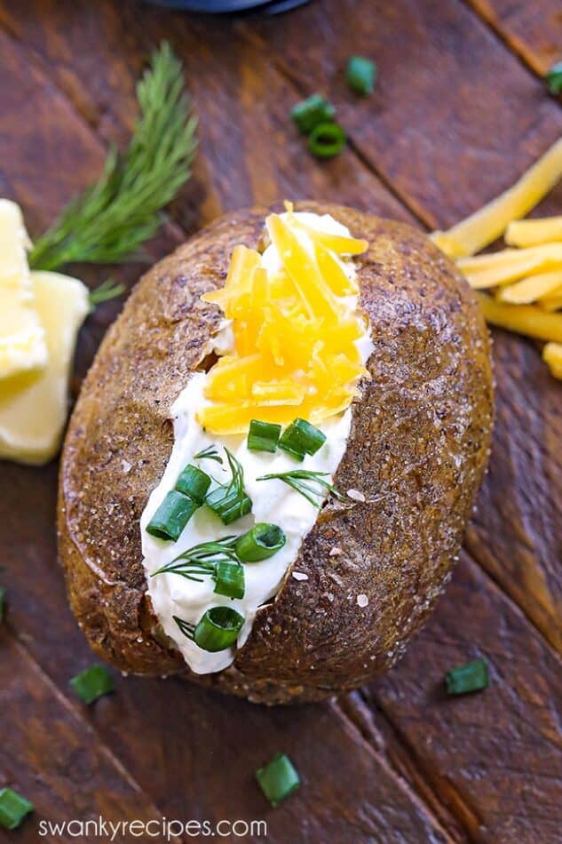 Air fryer baked potato topped with sour cream, cheese, and green onions