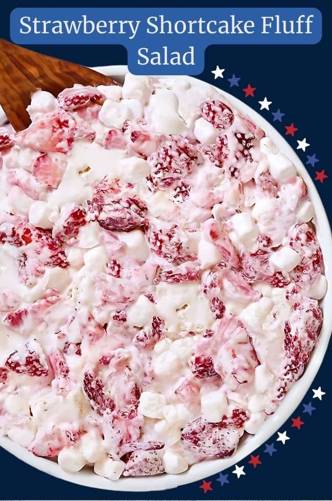 Strawberry shortcake fluff salad with chunks of pound cake in bowl mixed together with sliced strawberries, mini marshmallows, and whipped cream.