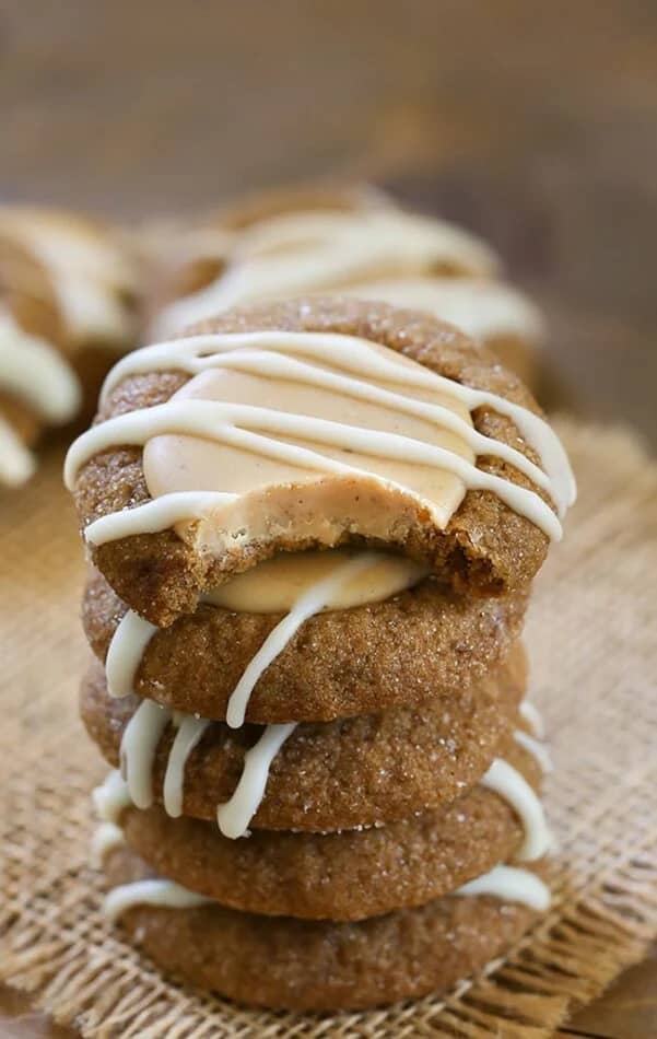 Stack of gingerbread thumbprint cookies drizzled with vanilla icing, highlighting the soft center and festive appearance.