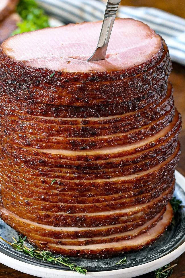 A maple glazed ham served on a double plate with a fork coming out the top of the ham stack.