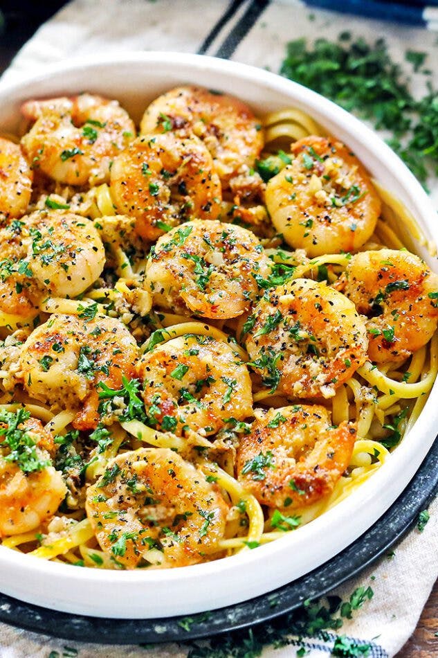 Shrimp scampi served in a bowl with pasta and tossed in a scampi sauce.