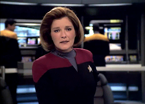 Animated GIF: The camera circles around Captain Janeway as she smiles and looks around at her crew.