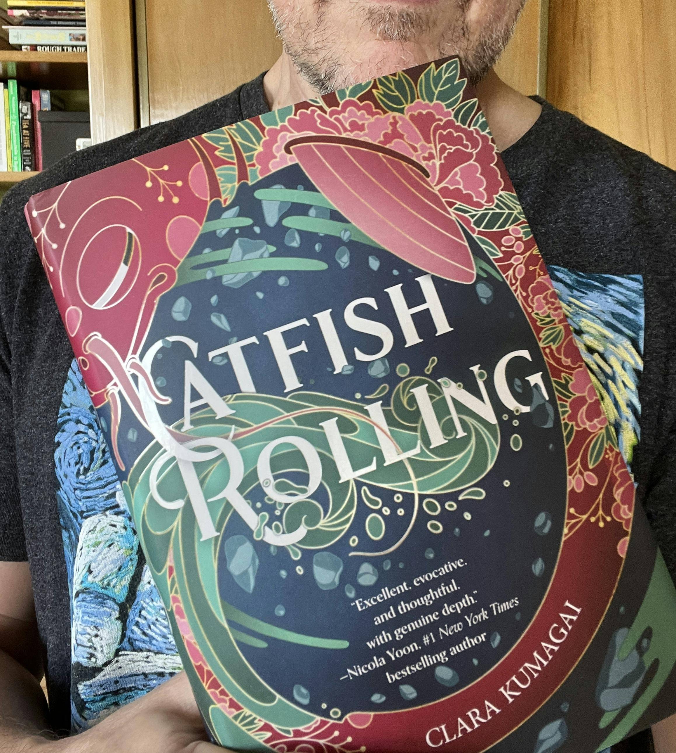 Here you can see the lower half of my face but that's not the focus. I'm holding a copy of Clara Kumagai's book, CATFISH ROLLING.