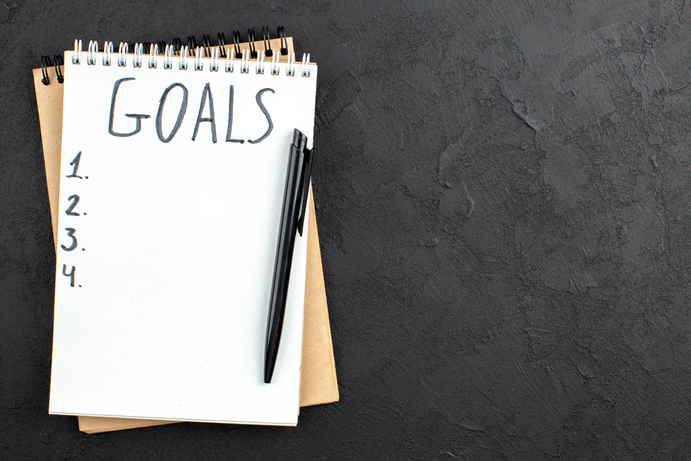 <a href="https://www.freepik.com/free-photo/top-view-goals-written-spiral-notepad-black-pen-black-with-free-space_17235127.htm">Image by KamranAydinov on Freepik</a>