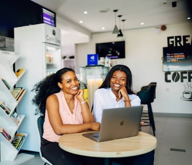 Two women sitting at a table with a laptop