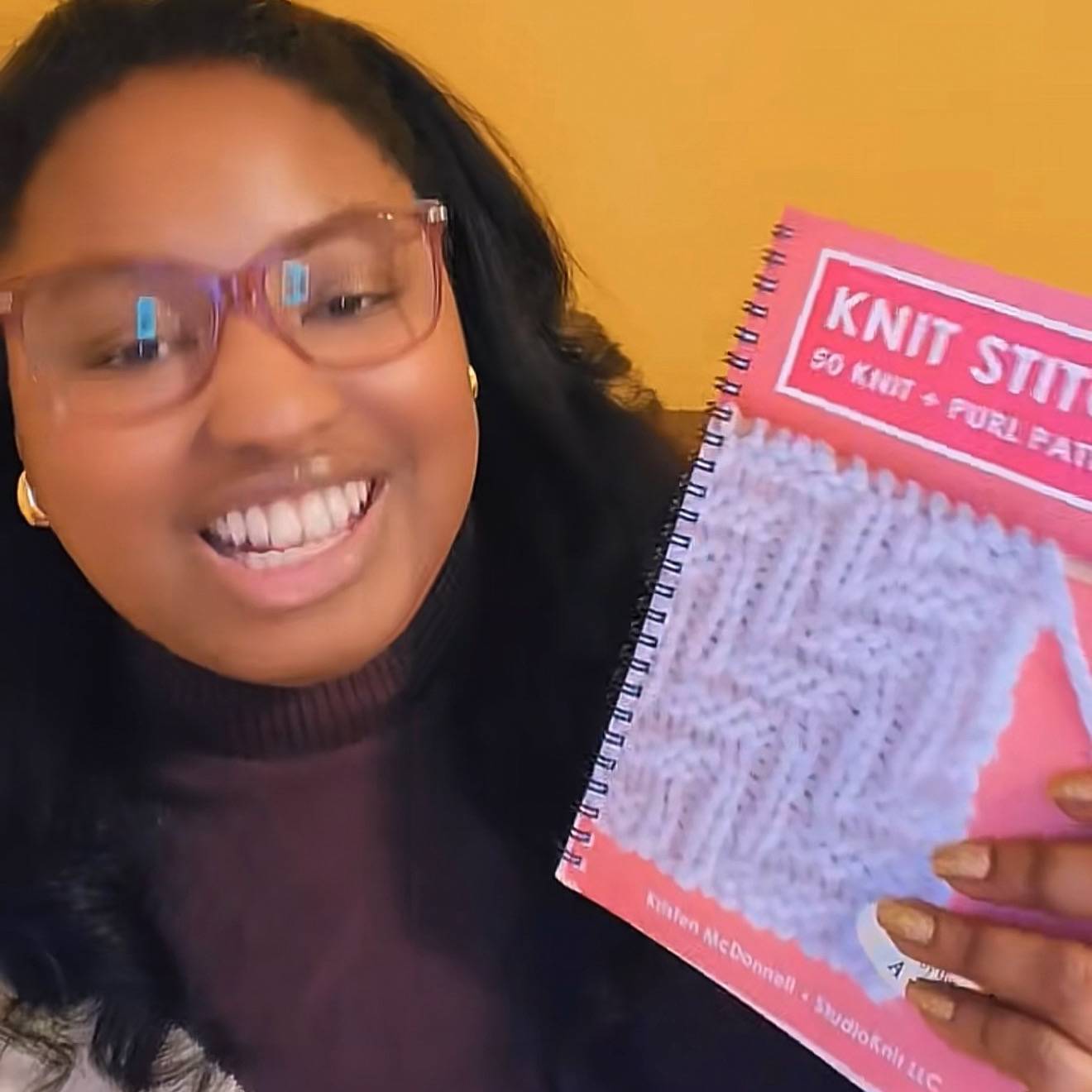 Knitter holding my Knit Stitch Book.