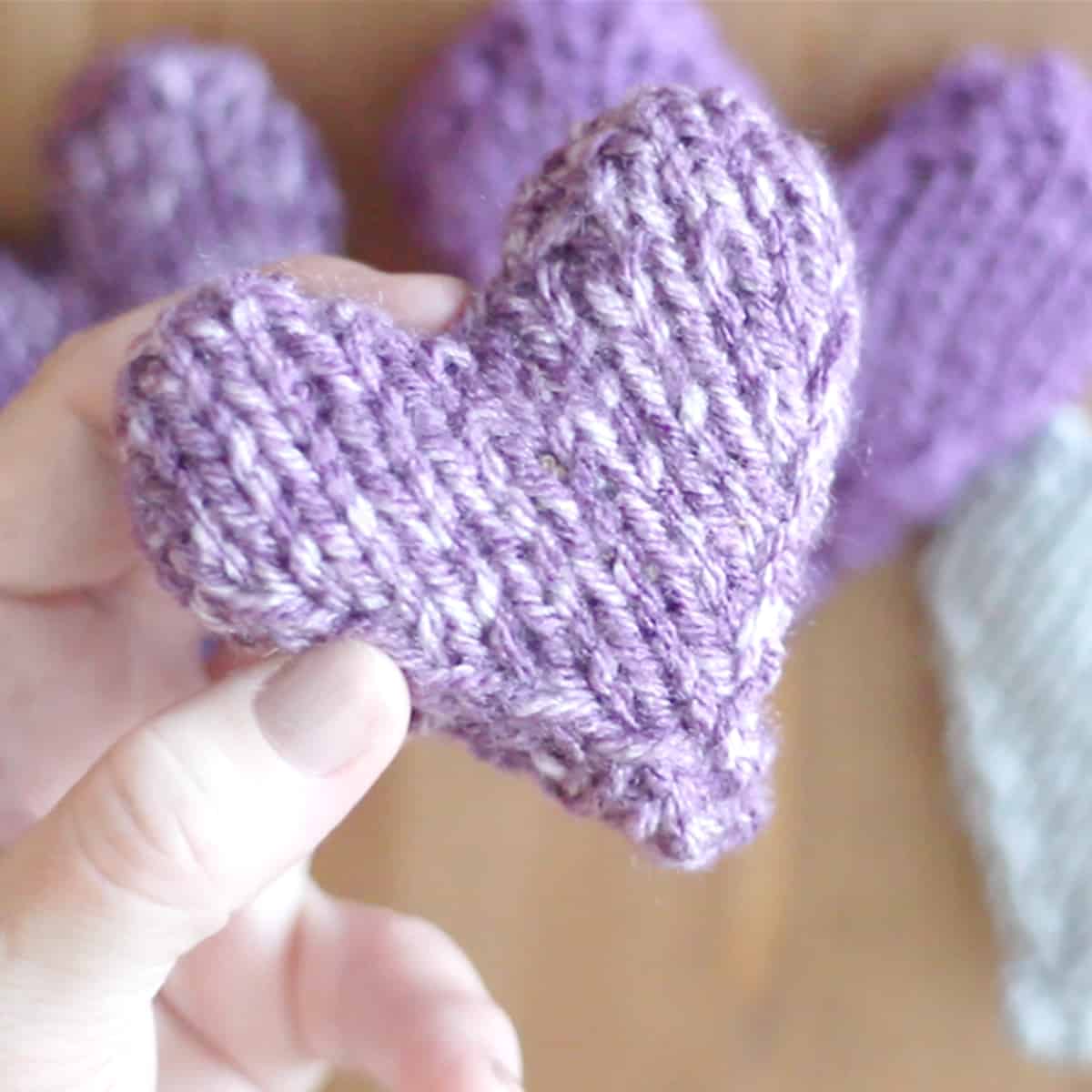 Knitted heart softie in purple yarn.