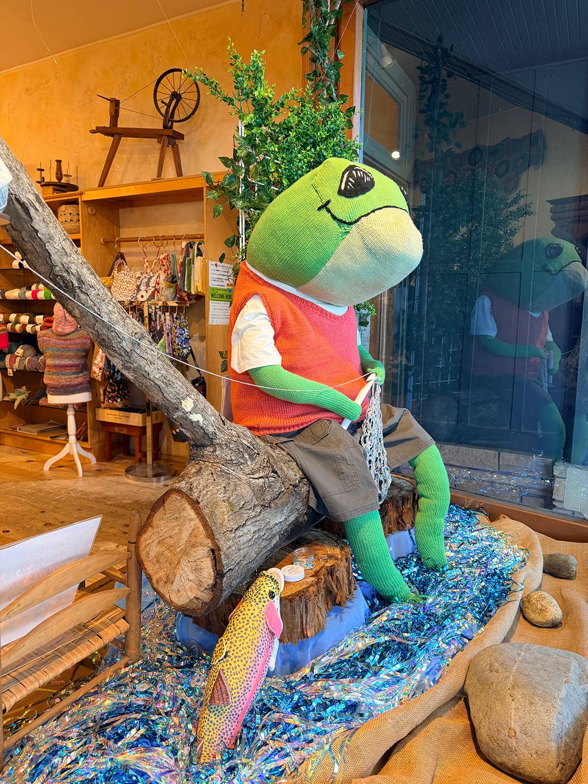 A knitted frog in a display window.