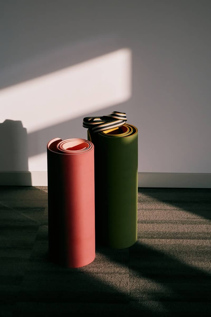 Two rolled yoga mats stand against a wall.