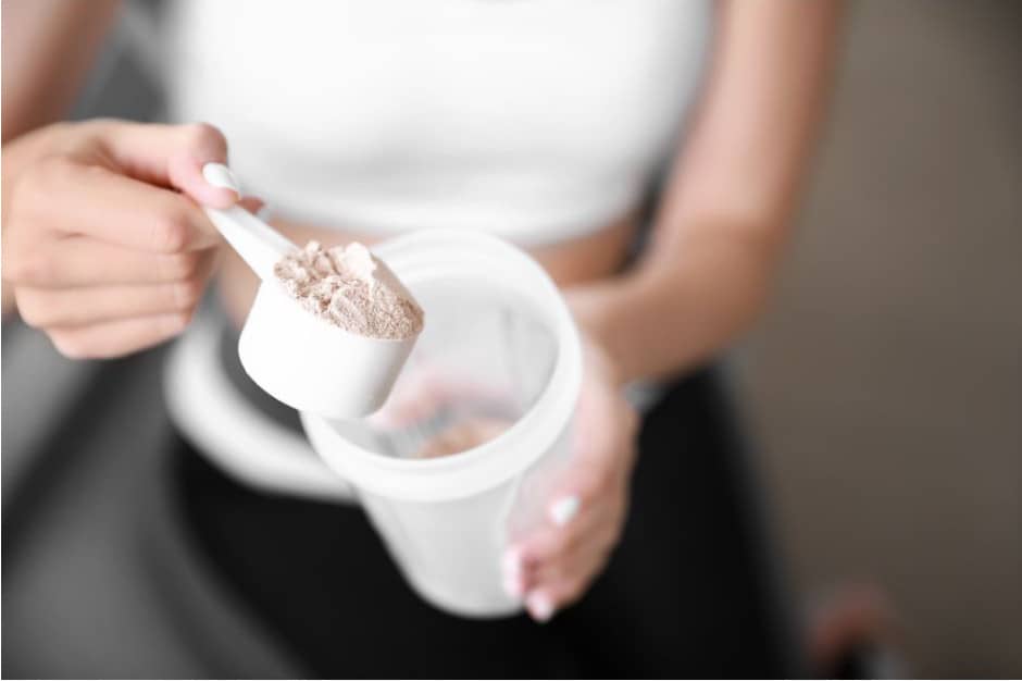 A woman putting a scoop of protein powder in a cup