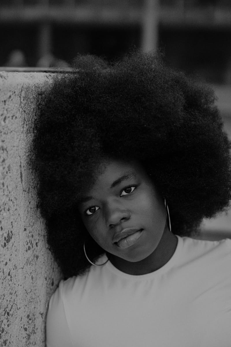 A woman with an afro leaning against a wall