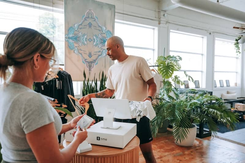 Detail of the SumUp Solo and POS system on a wooden counter, surrounded by plants in a design-focused retail store. A stylish, tech-forward solution for entrepreneurs who care about brand aesthetics.