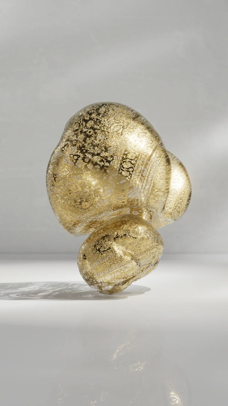 A gold, abstract sculpture floats on a reflective surface.