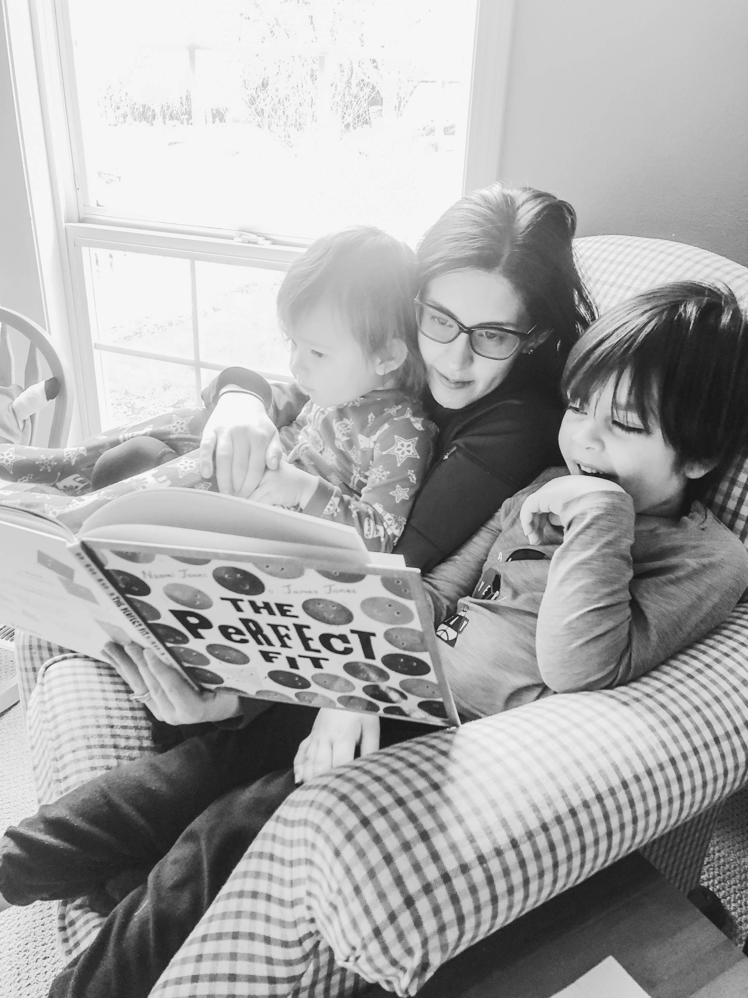 Mother with two children squeezed into a comfy chair reading a book entitled, The Perfect Fit