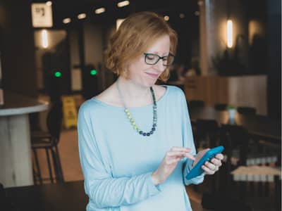 Lucy Davies - a woman with red hair, scrolling on her phone